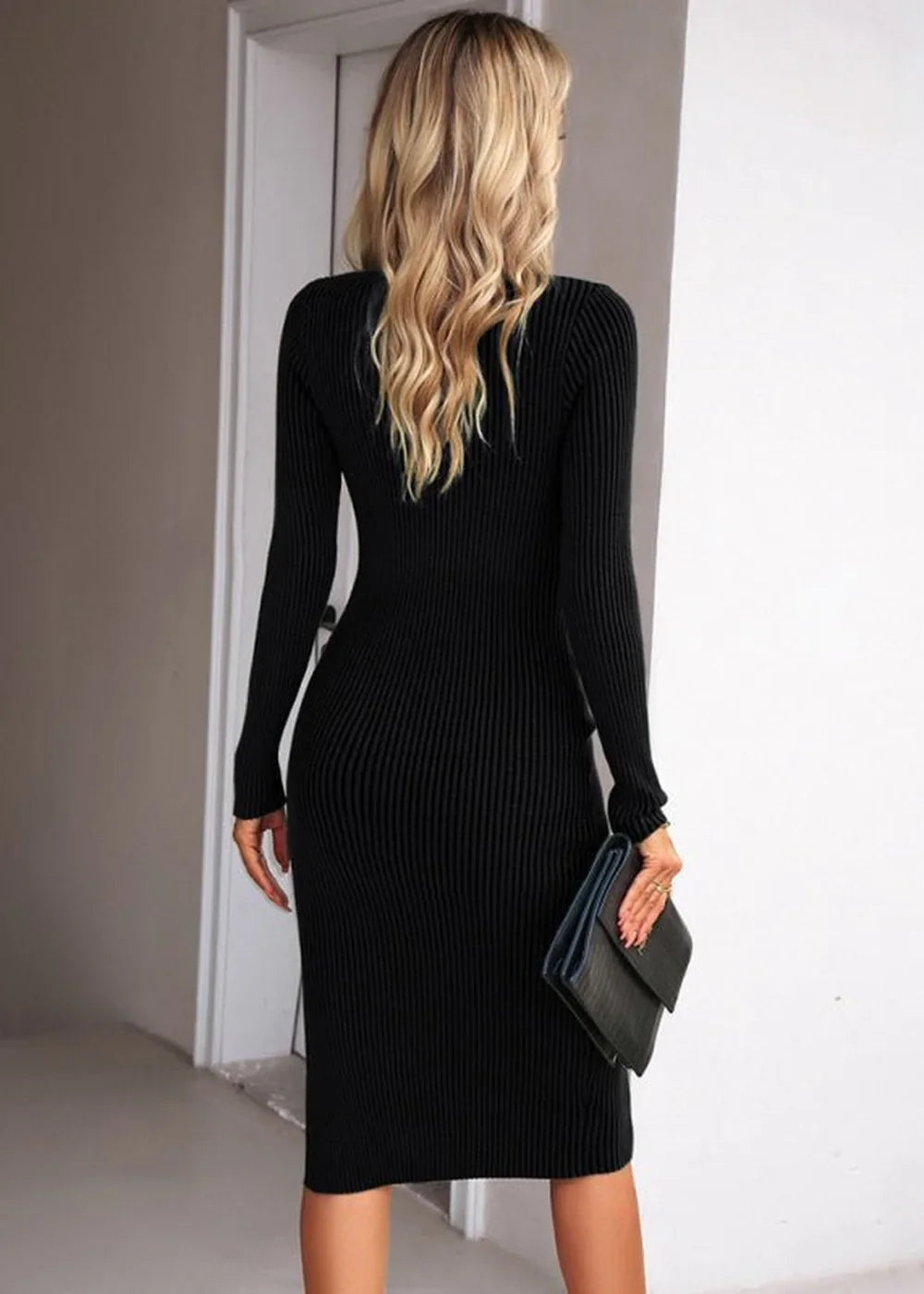Woman from behind wearing a black ribbed knit midi dress with long sleeves, holding a black clutch.