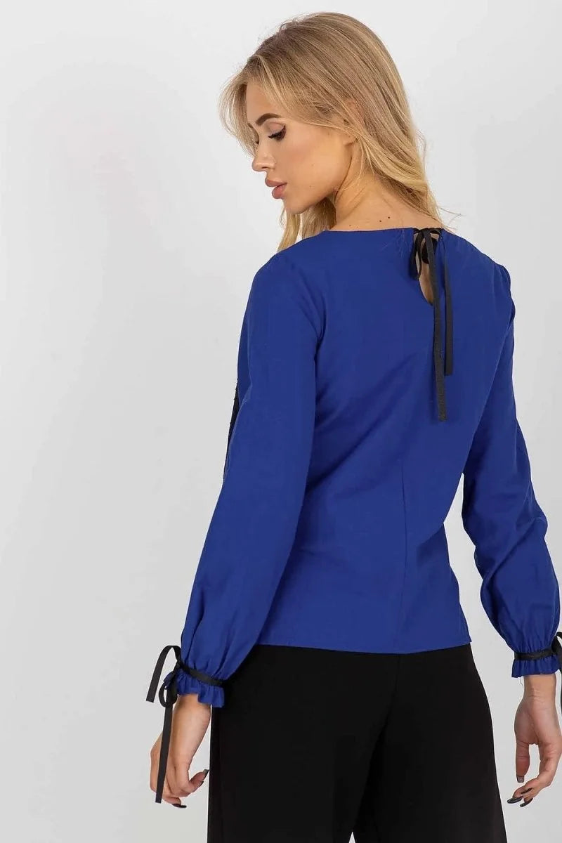 Royal blue long-sleeve top with tie details on cuffs and back, on model.
