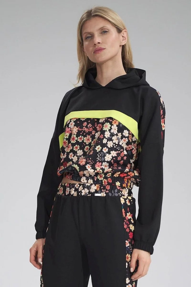 Black cropped hoodie with floral print panel and neon yellow stripe, on model.