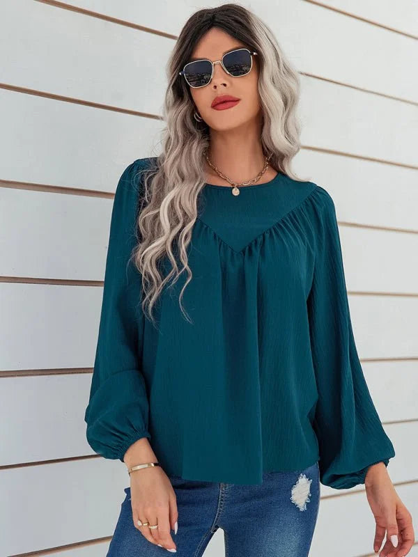 Teal peasant blouse with gathered neckline and voluminous sleeves, worn by a model.