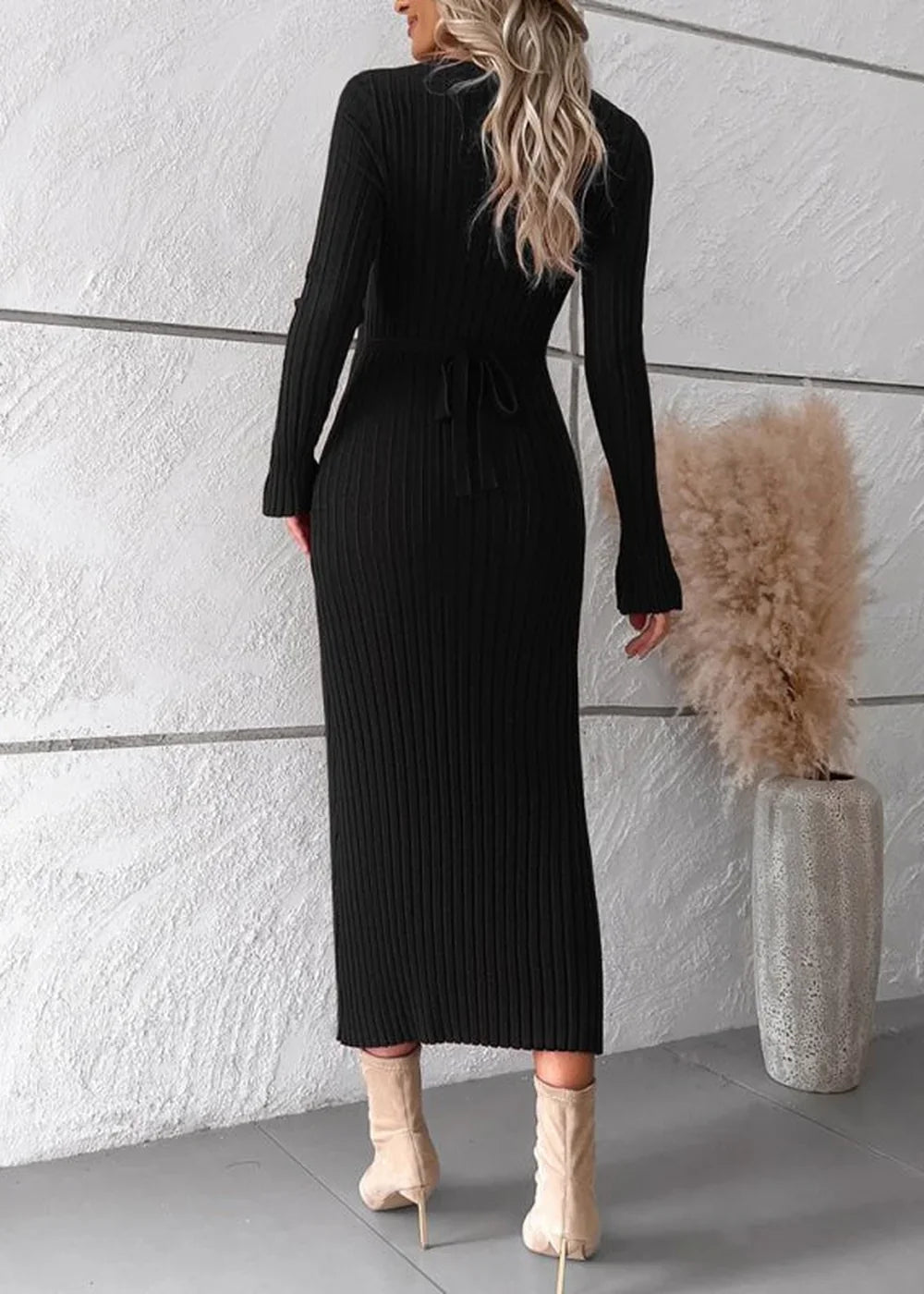 Black ribbed long-sleeve maxi sweater dress with a tie waist, worn with cream ankle boots.