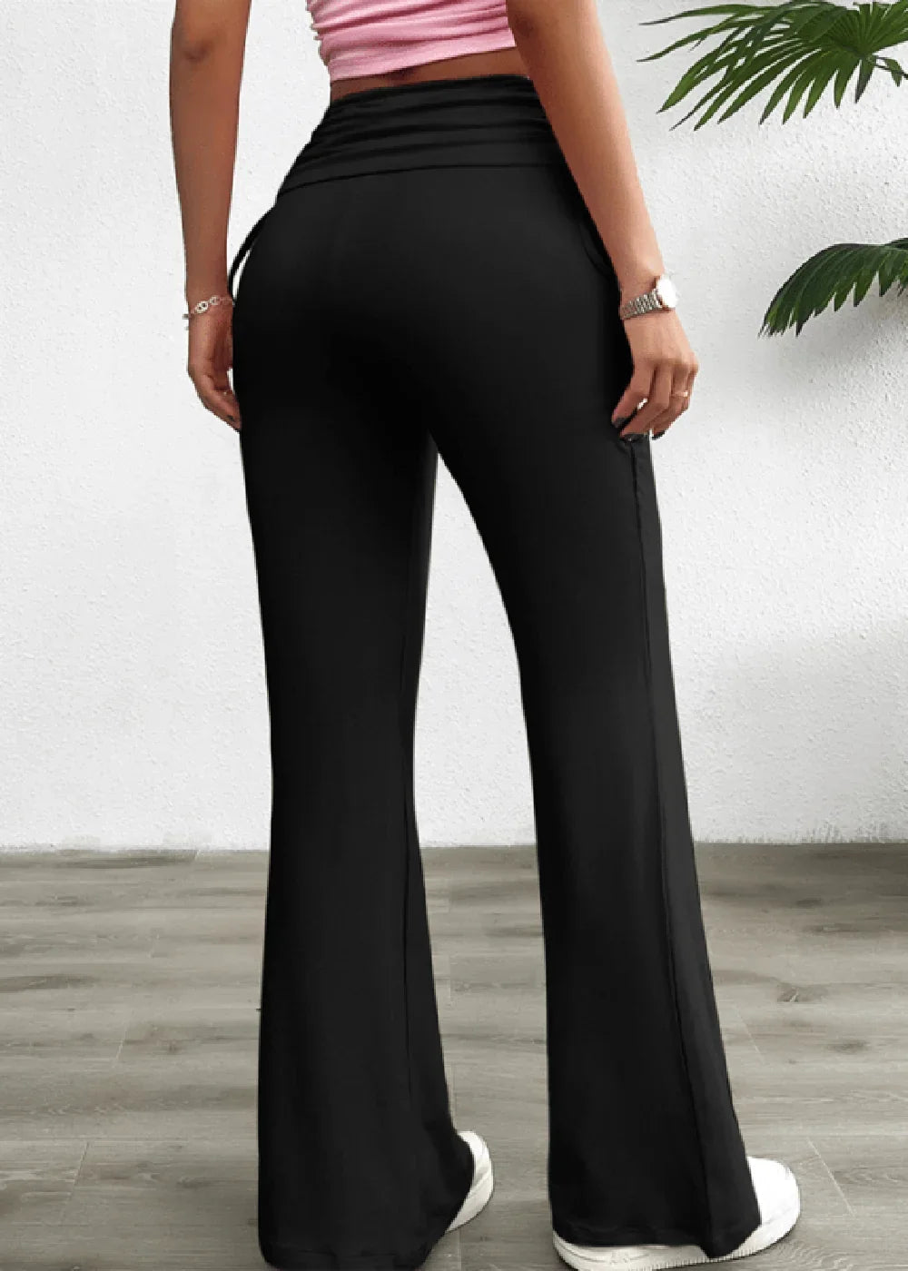 Black flared pants with ruched waist detail, shown from the back on a model.