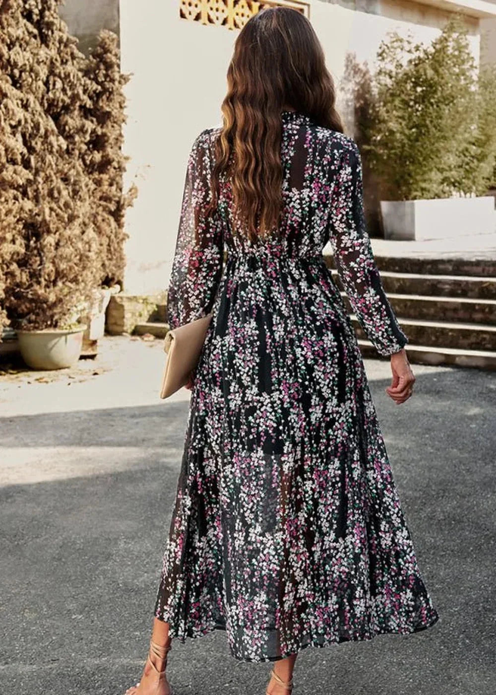 Black floral maxi dress with long sleeves, cinched waist, and a tan clutch.