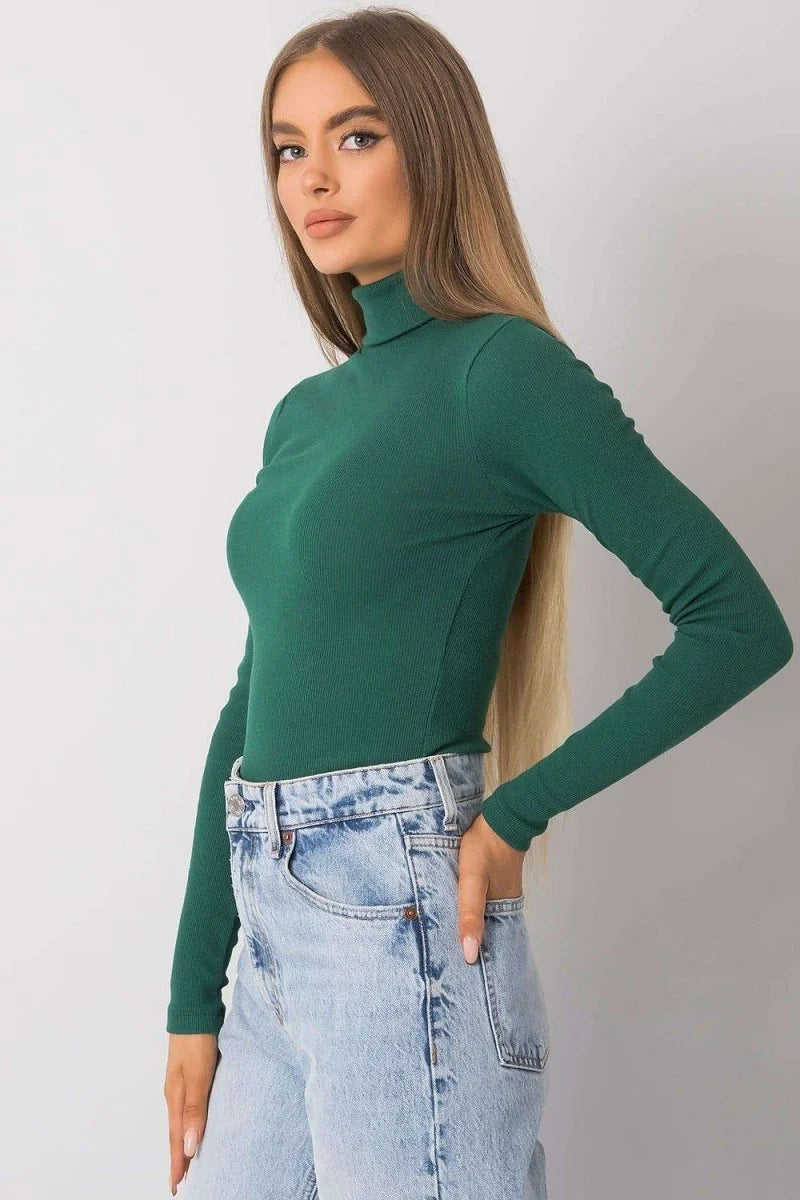 Fitted dark green ribbed turtleneck top with long sleeves, paired with light wash denim jeans.