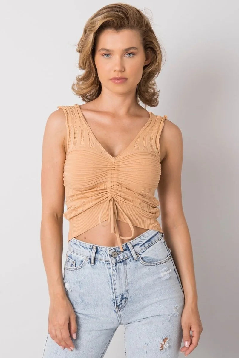 Peach acrylic knit ruched tank top with a drawstring tie and v-neck, paired with light wash distressed denim jeans.