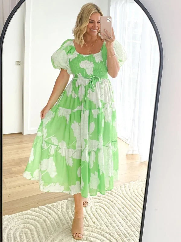 A woman wearing a lime green tiered midi dress with a white floral print and puff sleeves.