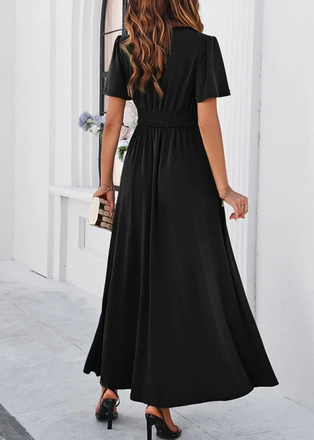 Black maxi dress with smocked waist and flutter sleeves, shown from the back on a model.