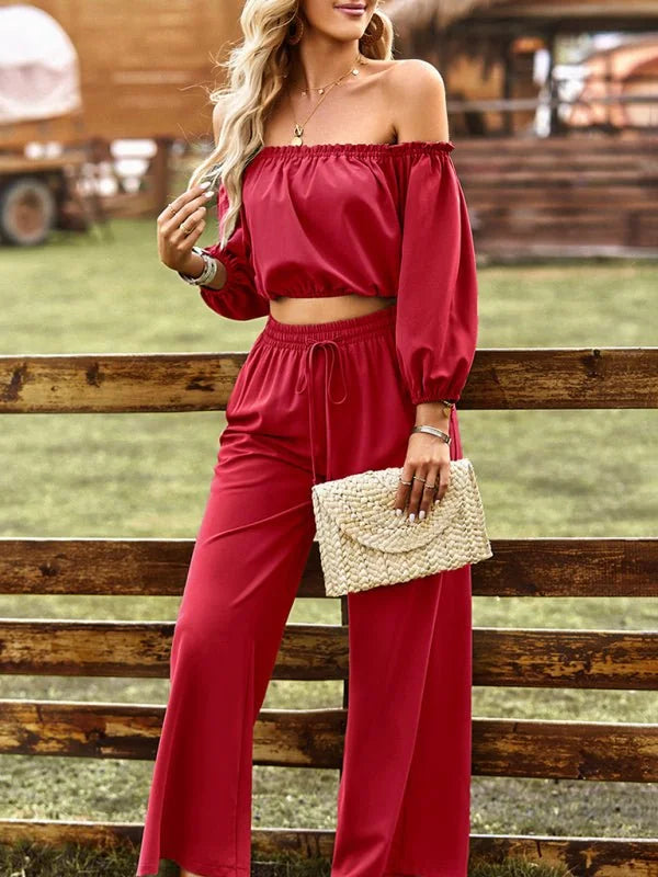 Red off-the-shoulder crop top and wide-leg pants suit with a straw clutch.