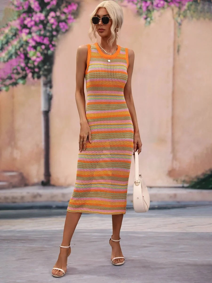 Woman in a sleeveless, striped knit midi dress with orange, pink, and green stripes, carrying a white purse.