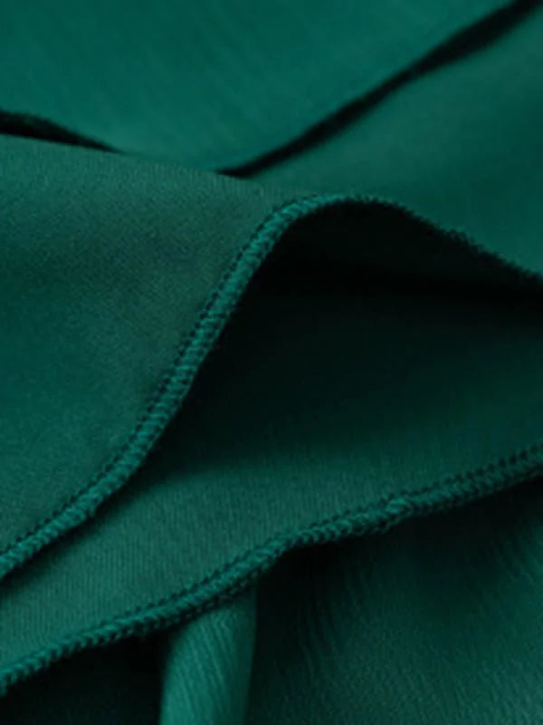 Close-up of a deep emerald green polyester fabric with a subtle ribbed texture and stitched seams.