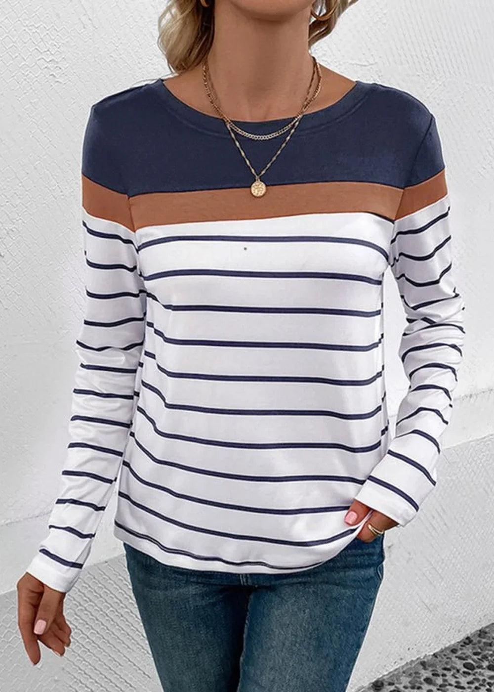 Navy blue, brown, and white striped long-sleeve top with a round neckline on a model.
