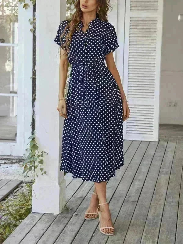 Navy blue rayon dress with white polka dots, V-neck, and belted waist, shown on a model.