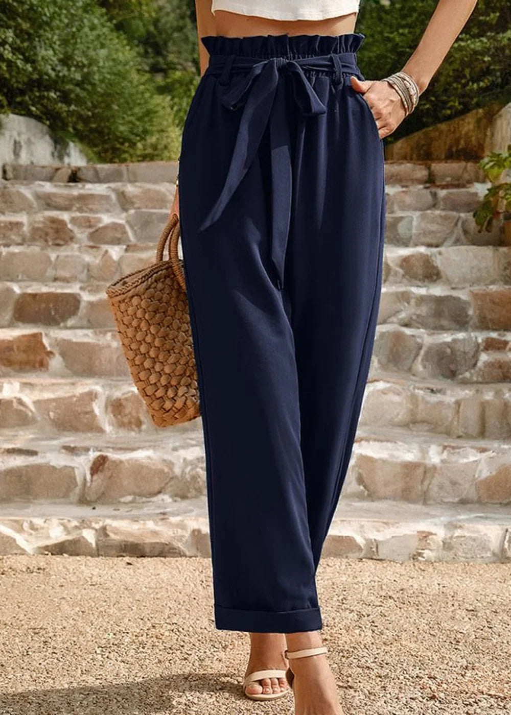 Navy blue paperbag waist pants with a tie belt and cuffed hems, shown on a model.