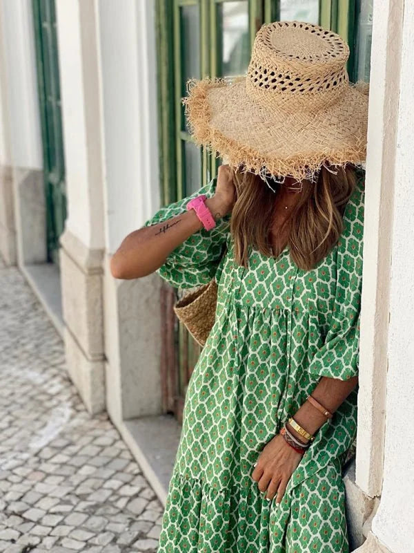 Green geometric print midi dress with frayed straw hat and bracelets on model.
