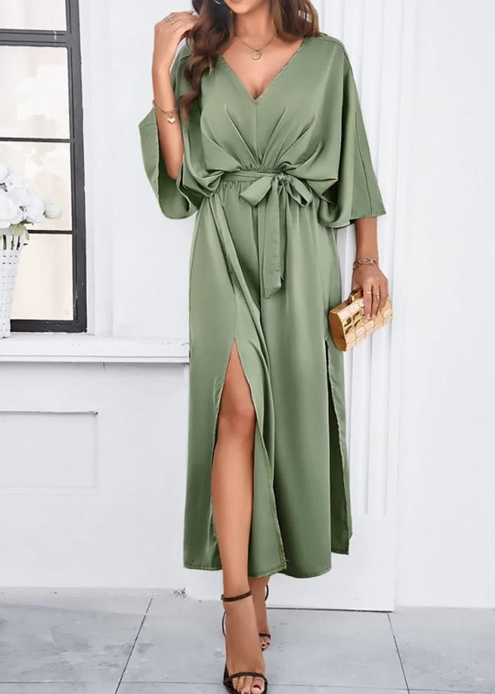 Sage green satin maxi dress with V-neck, tie waist, and high slits, on a model.