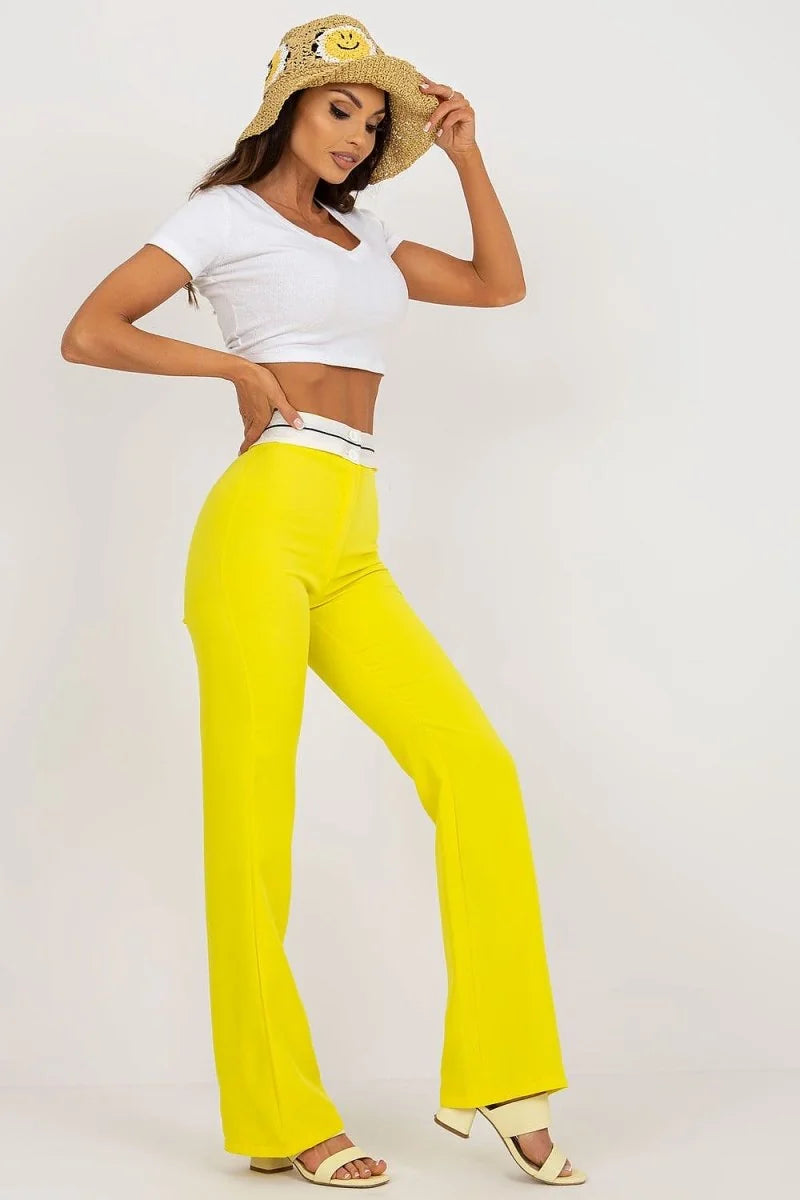 Bright yellow wide-leg pants with a white and black waistband, shown on a model.