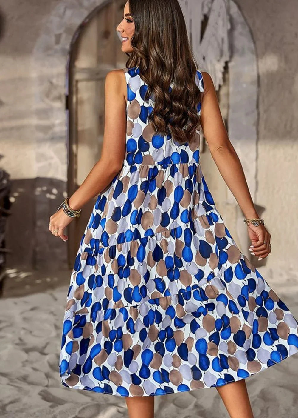 Woman in a tiered, sleeveless dress with a blue, brown, and white abstract floral print.