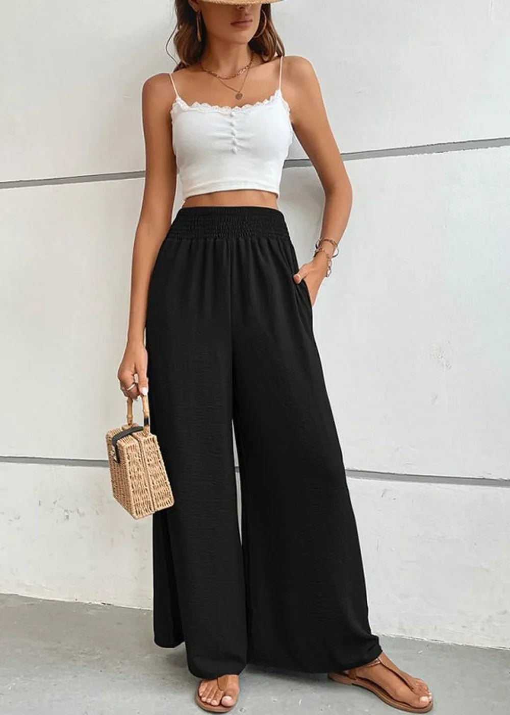 Black high-waisted wide-leg pants with textured fabric and a smocked waistband, shown on a model.