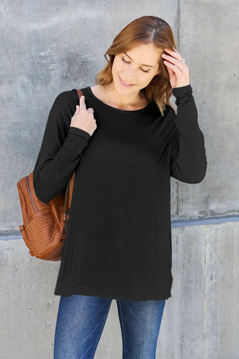 Black long-sleeve tunic top with a scoop neck, worn by a model with jeans and a woven brown backpack.