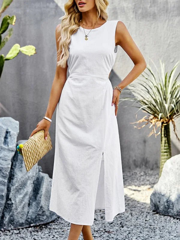 Sleeveless white midi dress with a side slit, worn by a model holding a straw clutch.