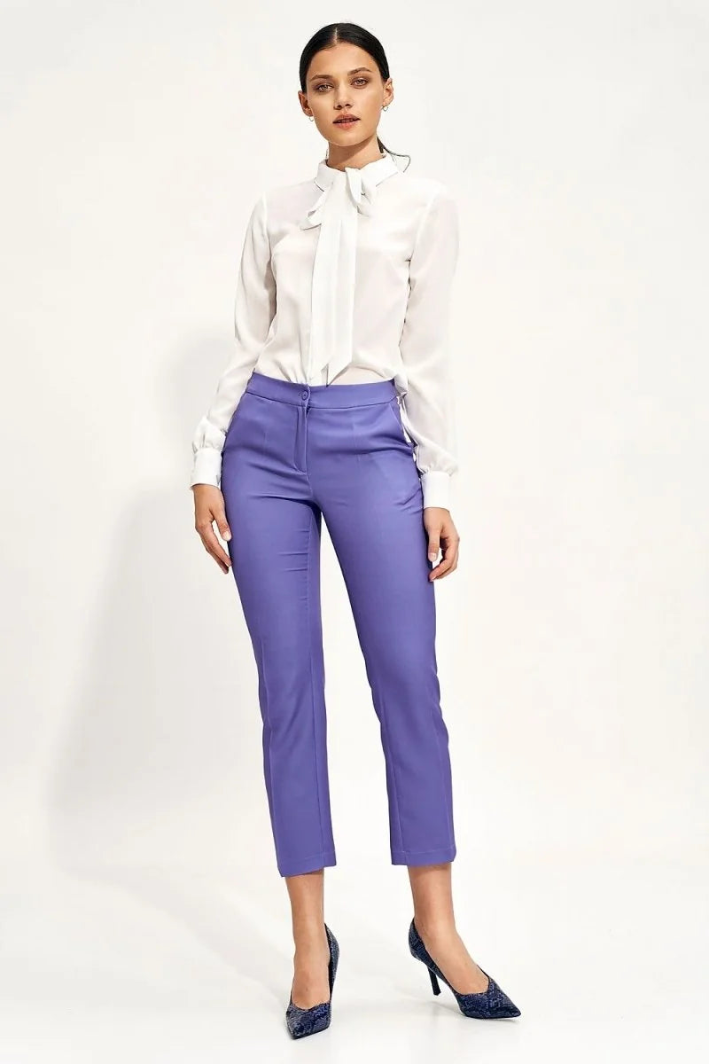 Full-length view of a woman wearing high-waisted, lavender, straight-leg pants with a fitted silhouette.