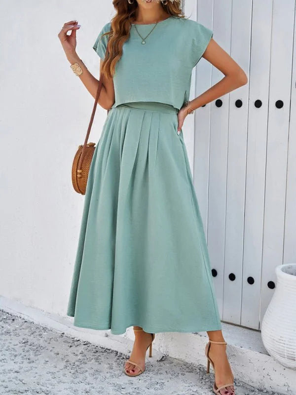 A mint green pleated midi skirt and cropped top set on a model.