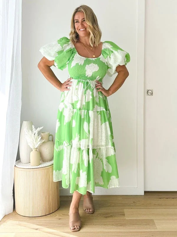 Green and white floral print tiered midi dress with puff sleeves and smocked bodice on model.