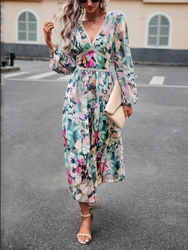 Woman in a flowing, long-sleeved midi dress with a colorful abstract floral print and v-neck.