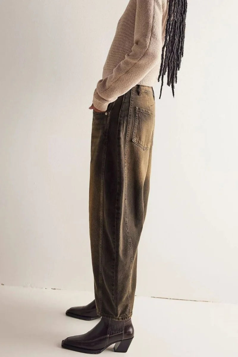 Relaxed fit brown jeans with visible stitching and pockets, shown on model.