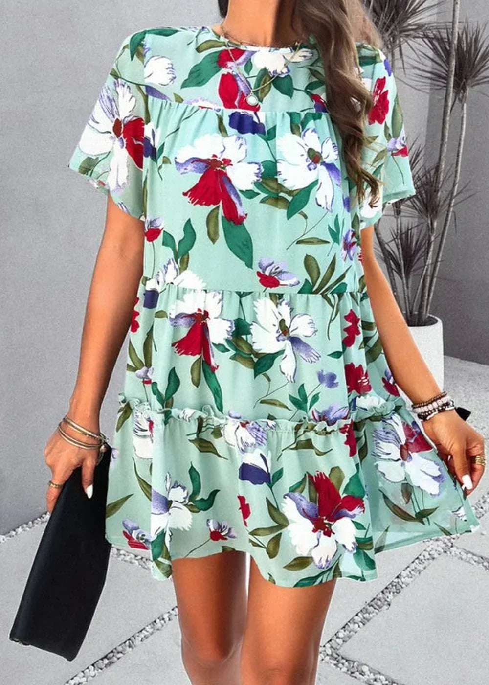 Light green tiered mini dress with a vibrant red, white, and blue floral print, short sleeves, and a ruffled hem.