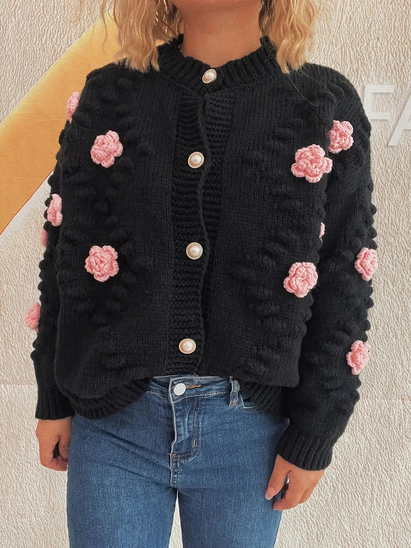Black knit cardigan with pink floral appliques and pearl buttons.