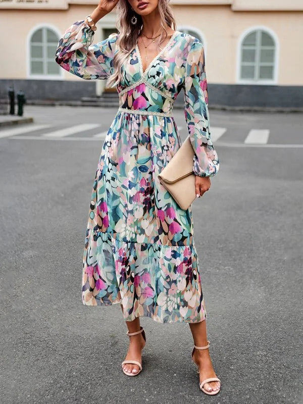 Flowy midi dress with a vibrant abstract floral print in pink, teal, and green, featuring a V-neck and long balloon sleeves.