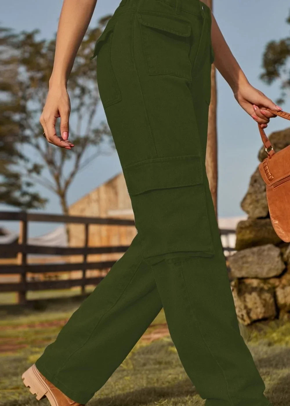Olive green cargo pants with large side pockets, worn by a model with a brown purse.