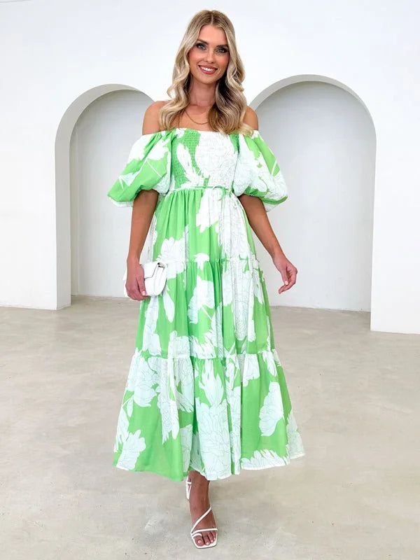 Off-the-shoulder lime green maxi dress with white floral print, tiered skirt, and puff sleeves on a model.