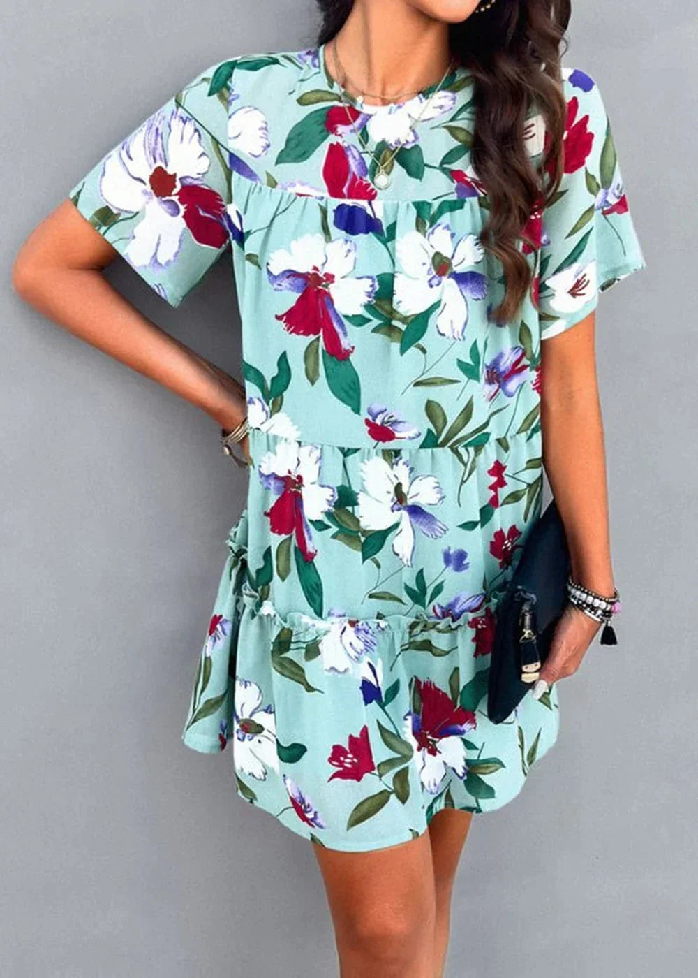 Light blue floral print tiered mini dress with short sleeves and a black clutch.
