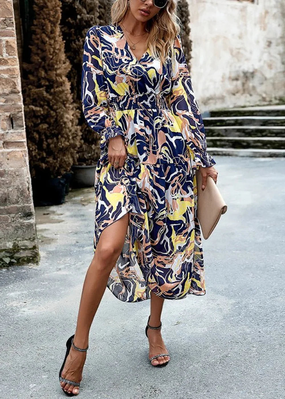 Woman in a navy, yellow, and peach abstract print midi dress with a V-neck and smocked waist.