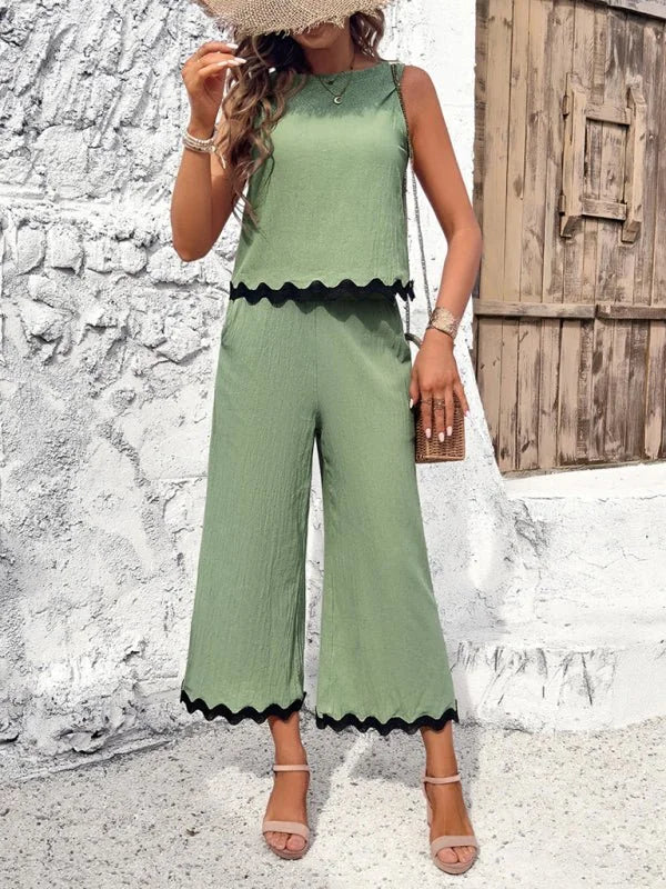 Sage green textured cropped pantsuit with black scalloped trim, on model.