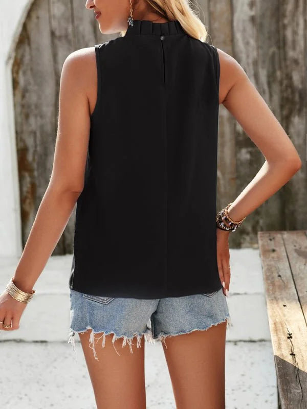 Back view of a black sleeveless mock neck top with frayed denim shorts and bracelets.
