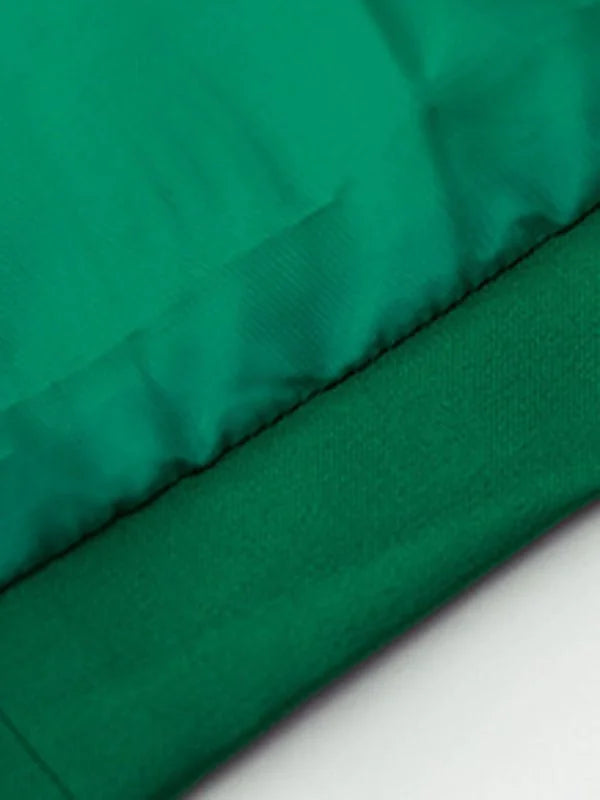 Close-up of a green blazer showing textured fabric and stitching detail.