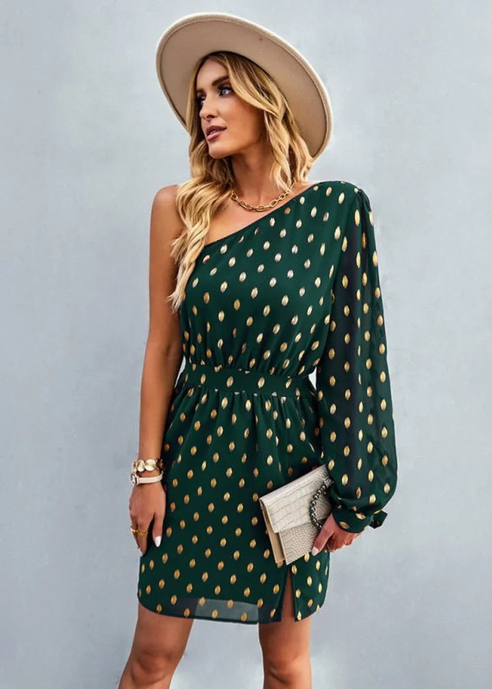 Green one-shoulder dress with gold polka dots, cinched waist, on model.