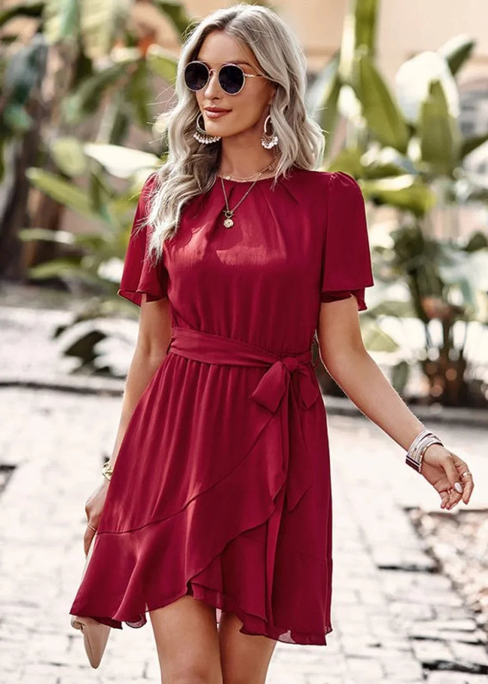 Burgundy ruffled wrap dress with short sleeves and tie waist, worn by a model outdoors.