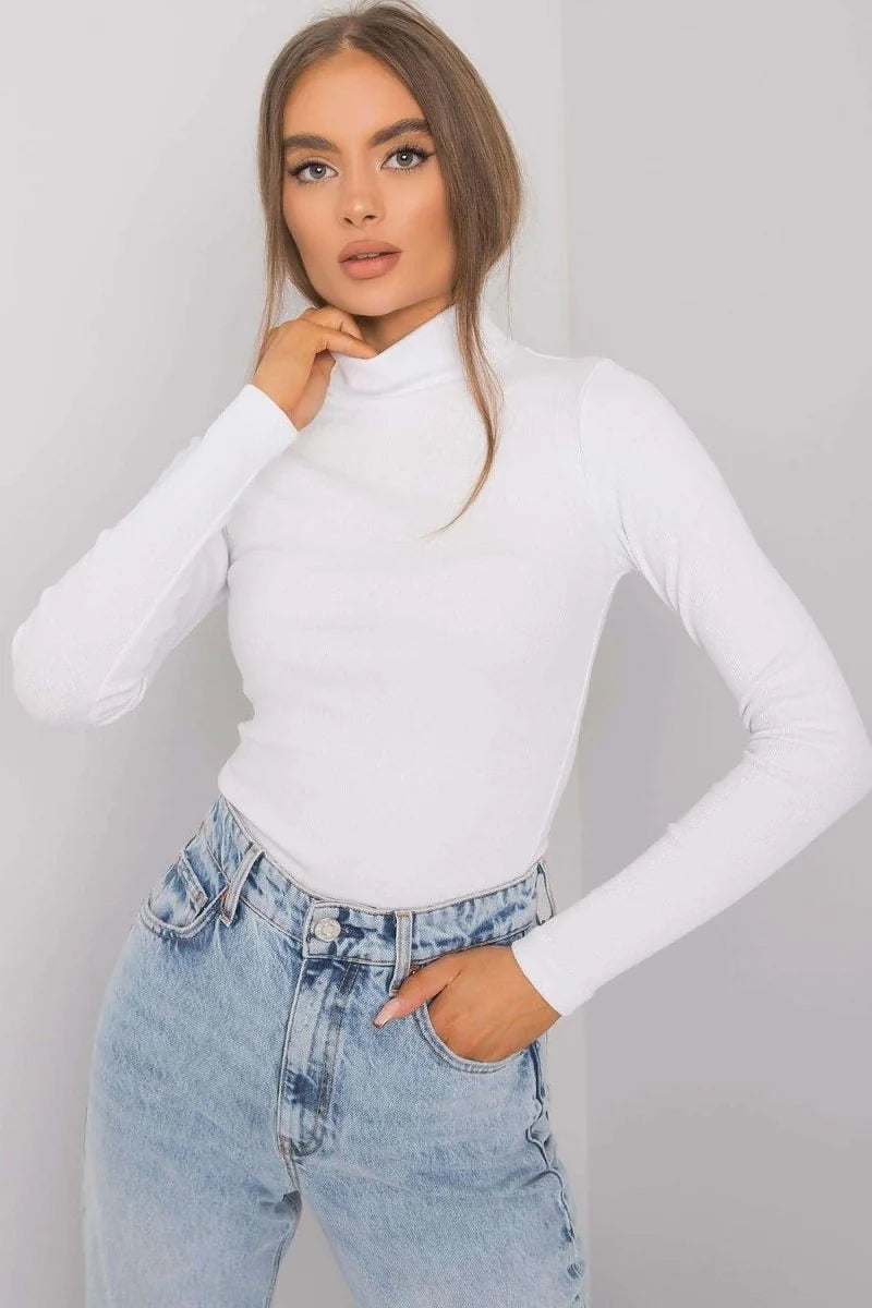 Fitted white turtleneck long-sleeve top with light wash denim jeans on a model.
