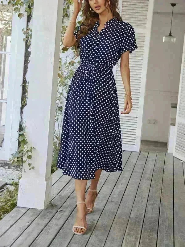 Navy blue polka dot rayon midi dress with belted waist and short sleeves on model.