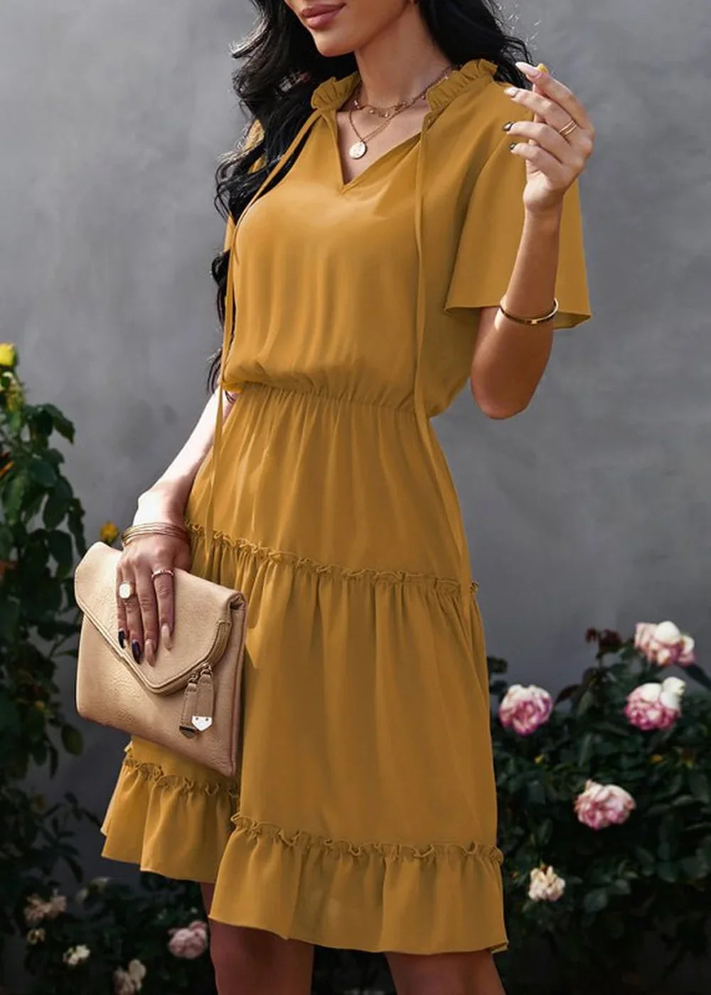 Gold ruffled V-neck tiered dress with elastic waist, worn by a model holding a clutch.