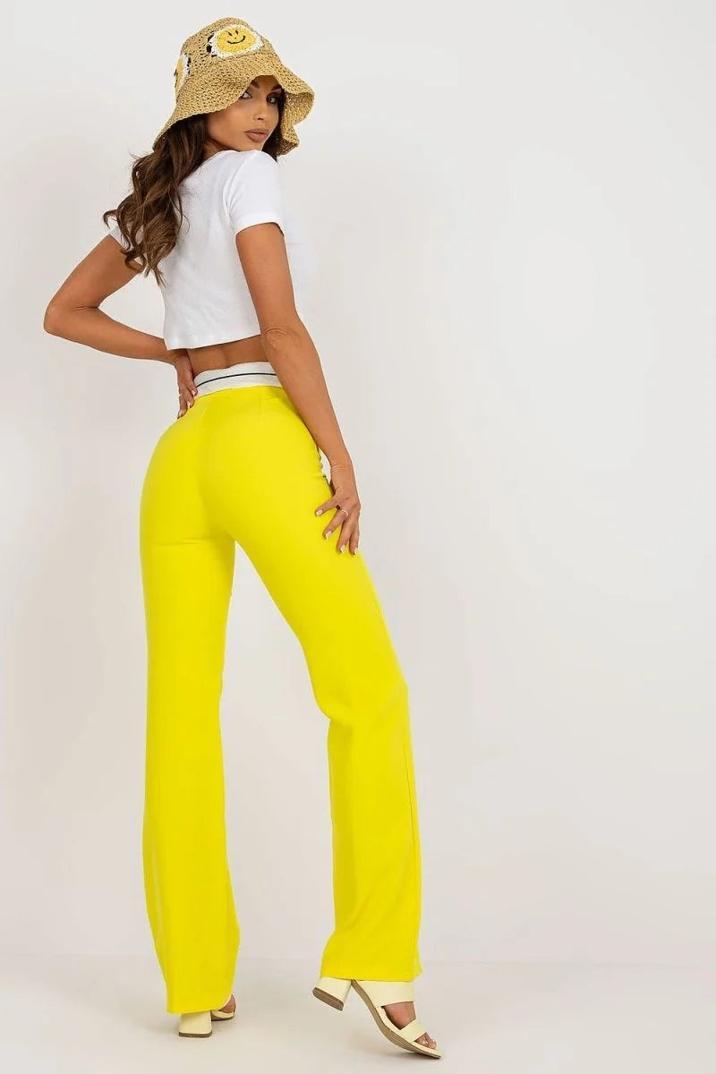 Bright yellow wide-leg pants with a white and black striped waistband, shown on a model.