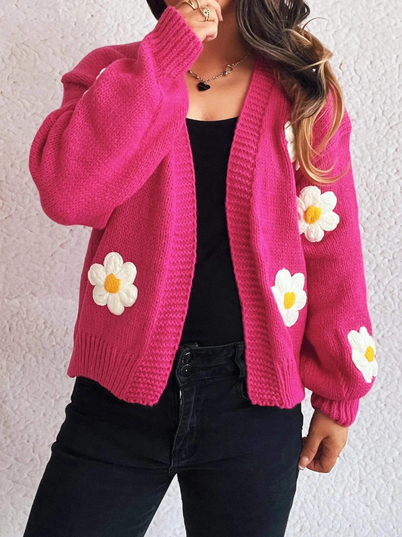 Bright pink knitted cardigan with white and yellow floral appliques.