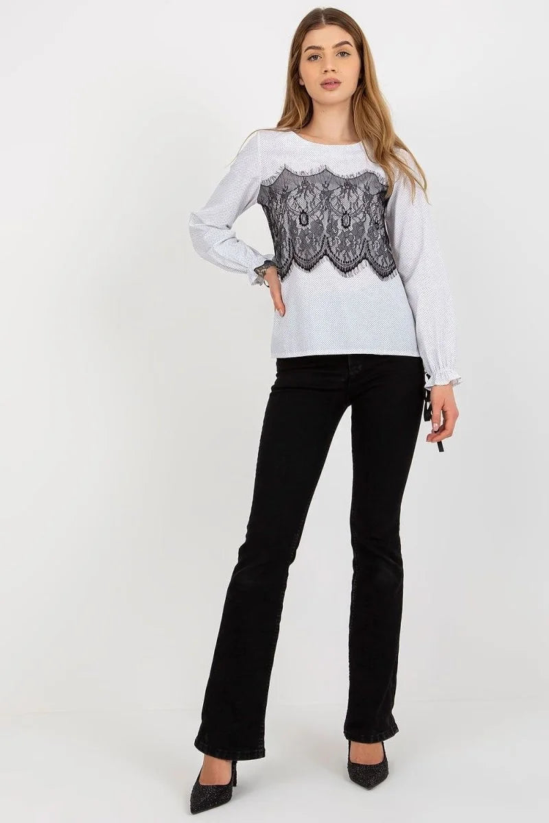 White long-sleeve top with black lace detail and black flared jeans on model.
