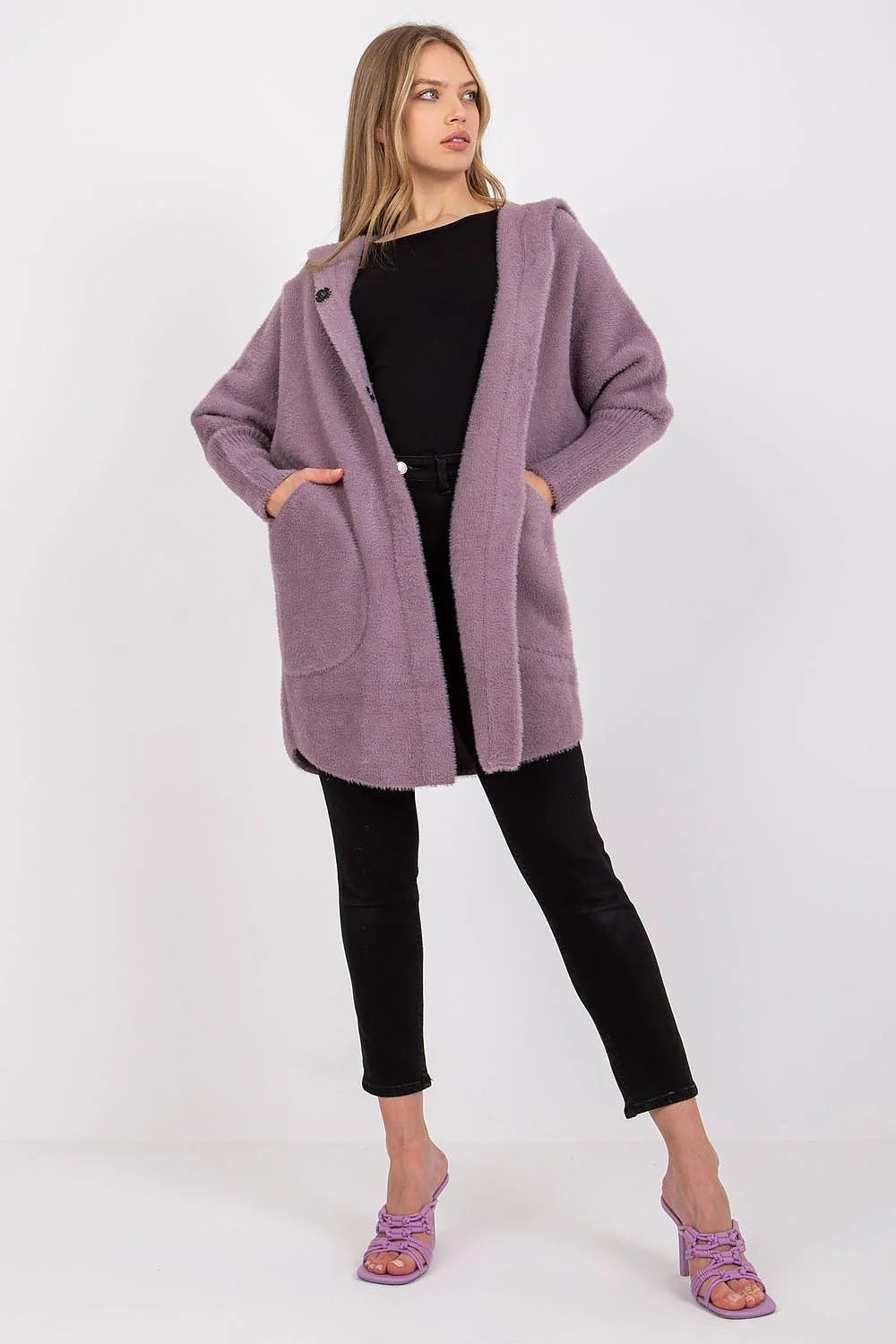 Lilac fuzzy hooded cardigan with pockets and button closure, on model with black pants and heels.