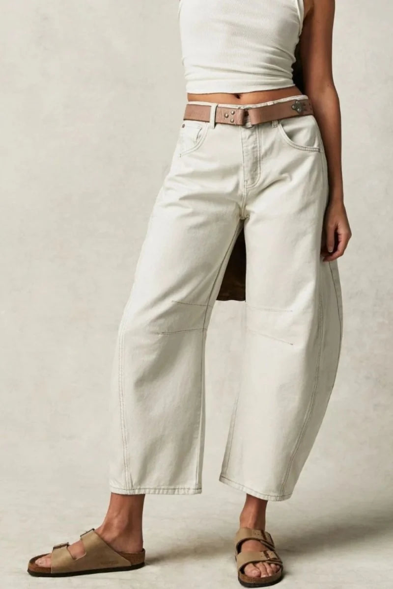 Relaxed fit, off-white cotton-blend pants with a brown belt and buckle, shown on a model.