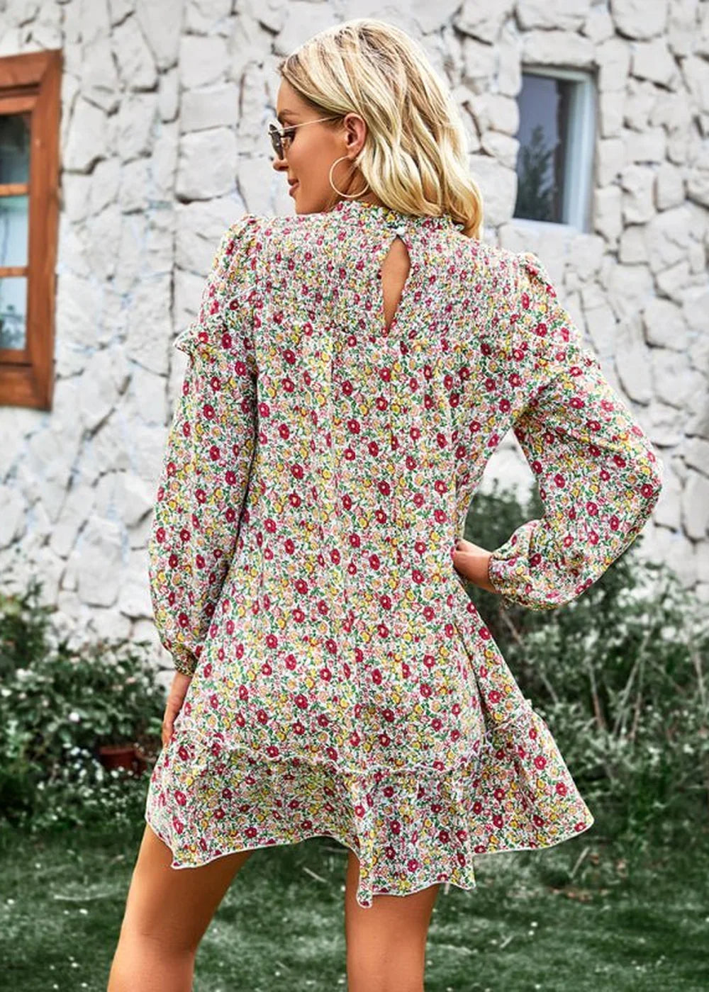 Woman in a flowy, floral print dress with puffed sleeves and a ruffled hem.